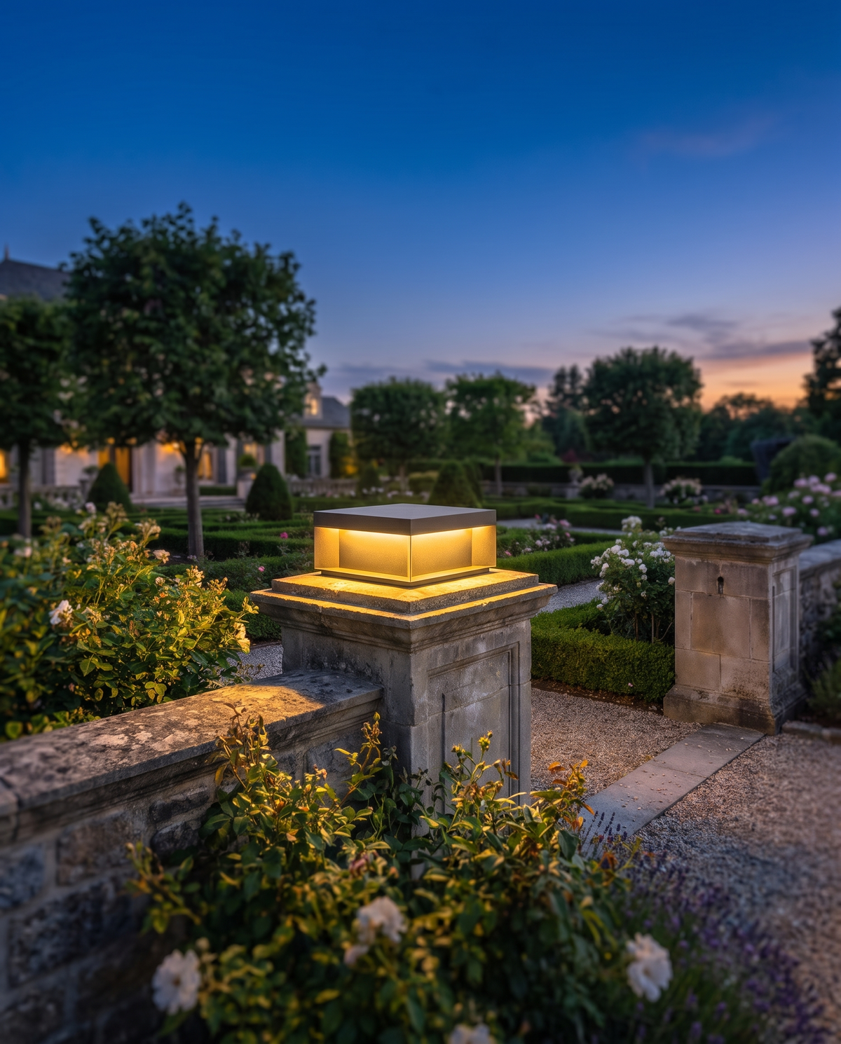 The Monarch Estate Pillar Lantern in a garden landscape at dusk, wide shot