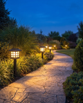Luxury solar pathway lantern lights lining a garden path at dusk, wide shot