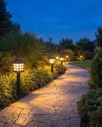 Luxury solar pathway lantern lights lining a garden path at dusk, wide shot