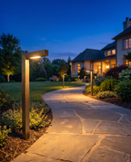 Luxury solid brass landscape path lights lining a stone walkway at dusk, wide shot